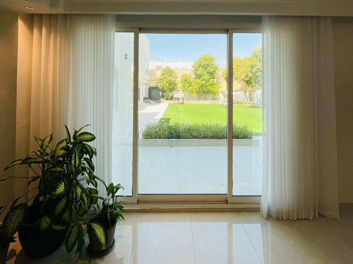 Elegant sliding glass door framing a lush garden with sheer white curtains